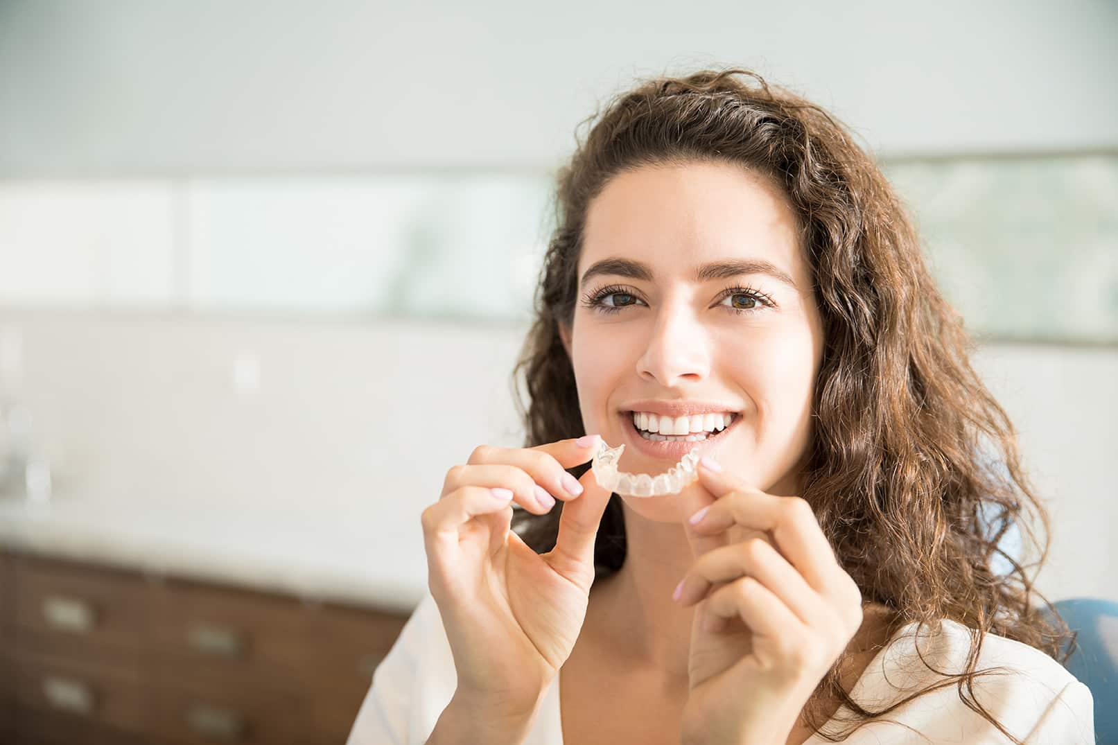 woman holding up suresmile clear dental aligners at Serenity Creek Dental Care